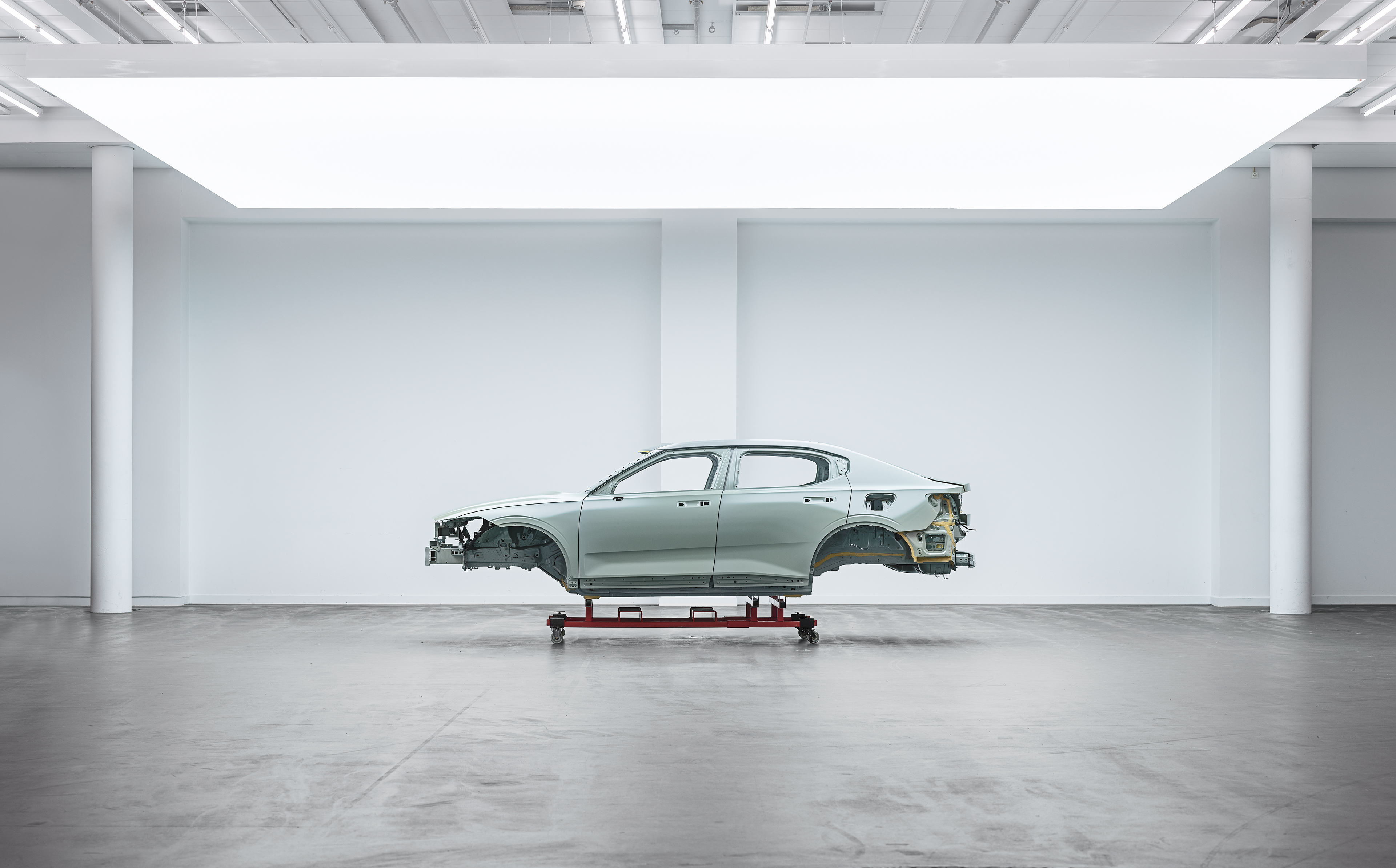  The body of a car sits raised in an empty warehouse.