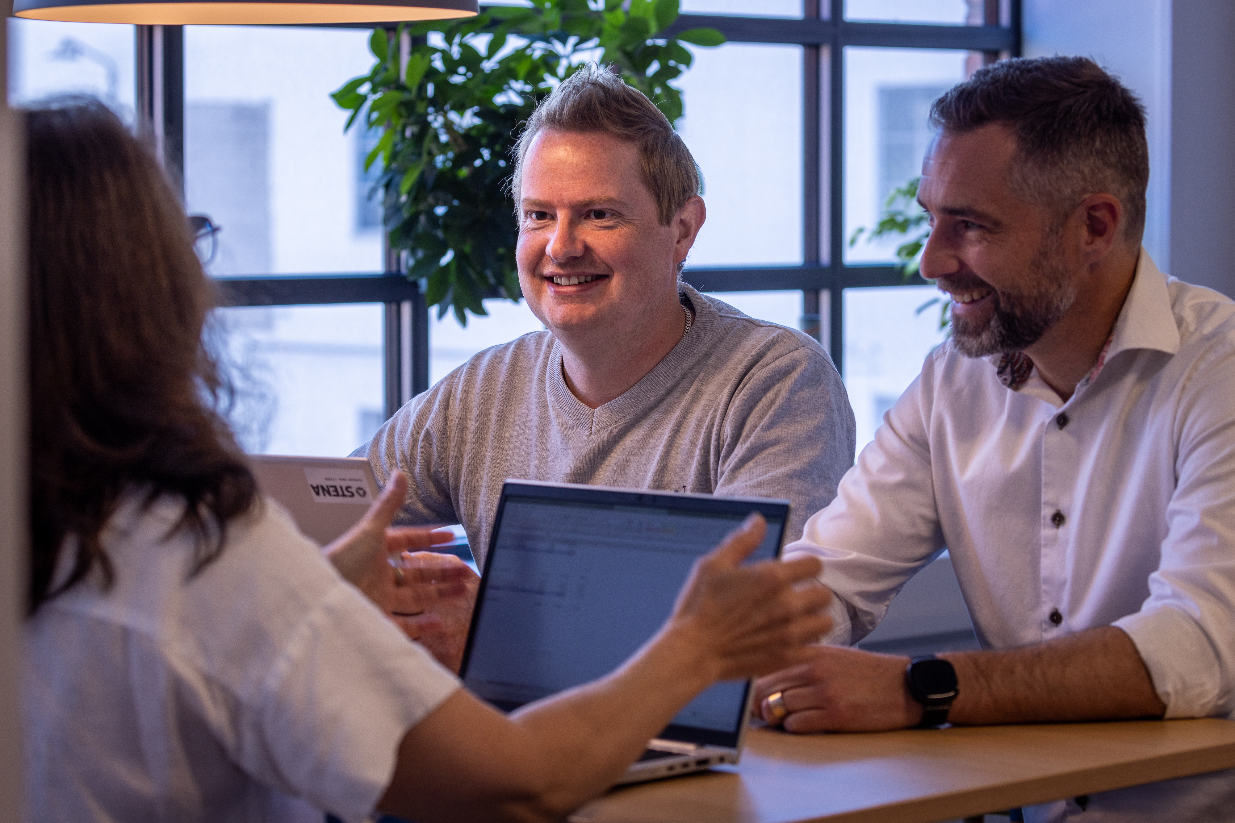Stena Aluminium-anställda sitter tillsammans vid ett bord och skrattar.