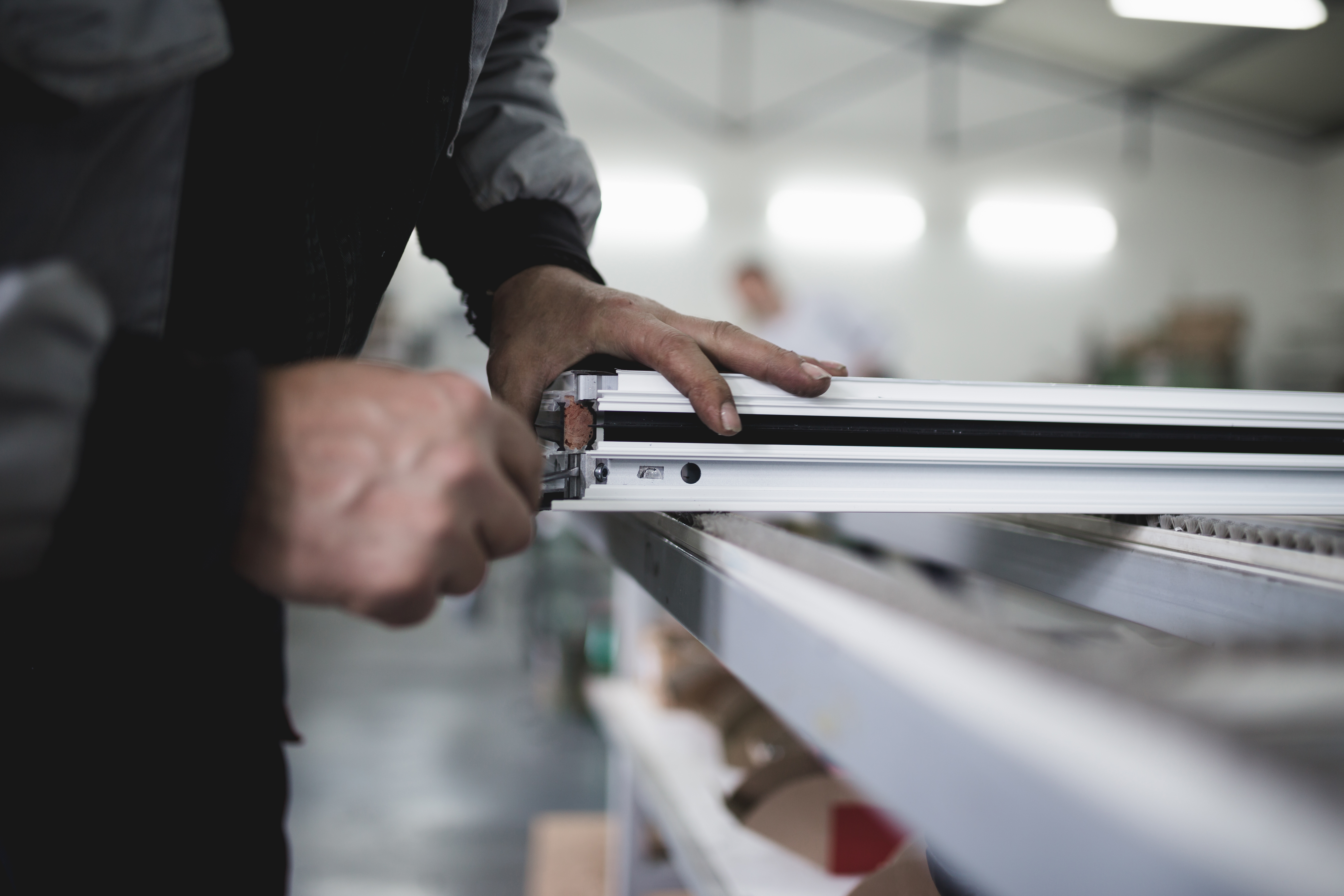Close-up of a worker placing aluminium inside of a windowframe.