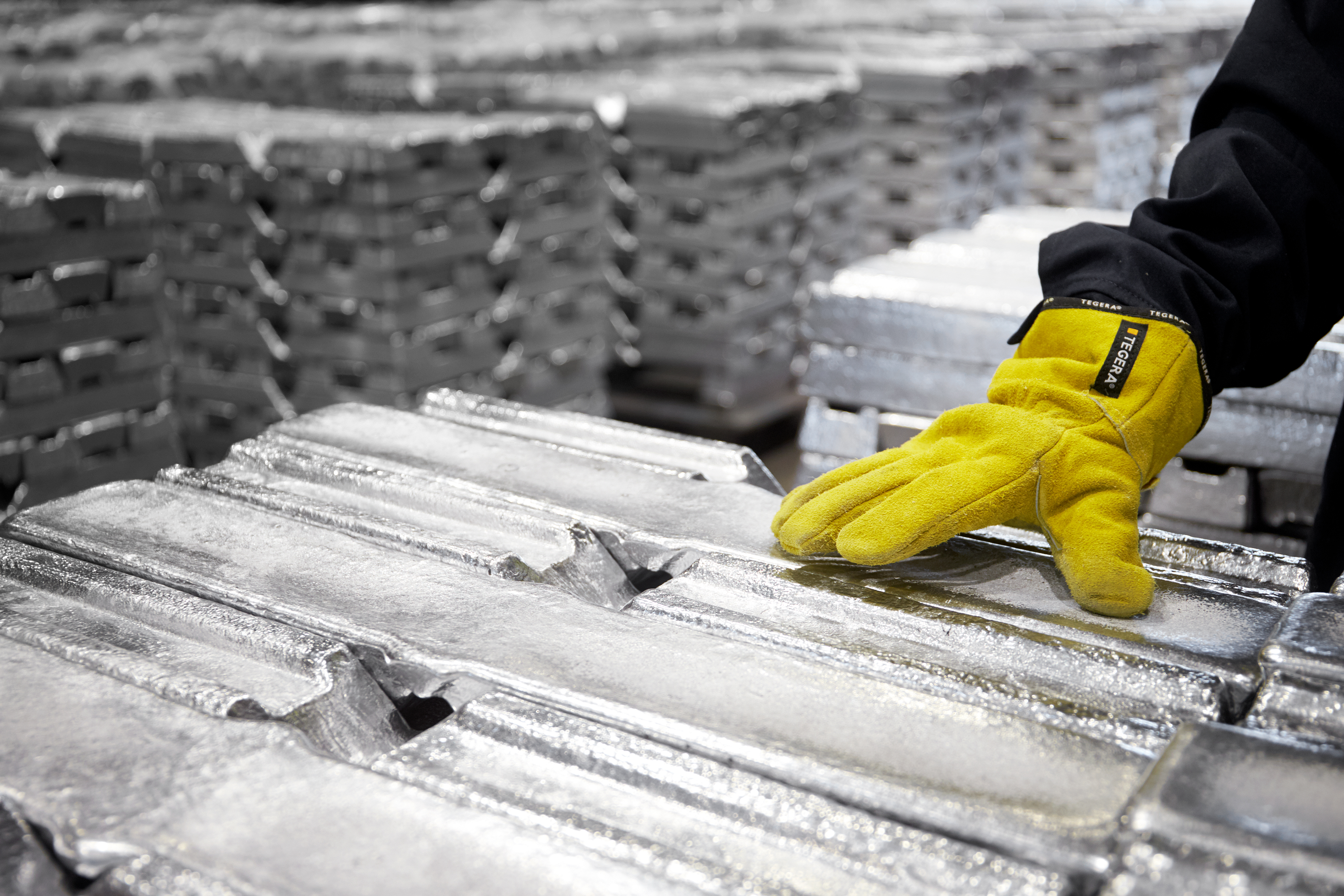 A Stena Aluminium employee's hand places upon some aluminium ingots